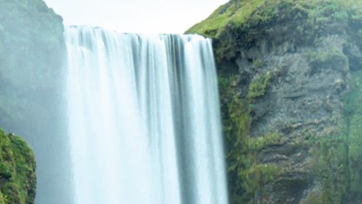 a waterfall surrounded by green vegetation and vertical rocks. It illustrates the potential for significant water savings by TrumpJet®